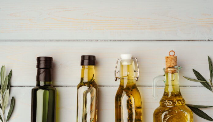 Glass bottle with olive oil on gray background
