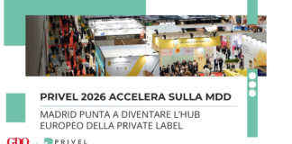 Aerial view of a crowded trade show with multiple booths and attendees, banners reading Italian branding visible in the background.