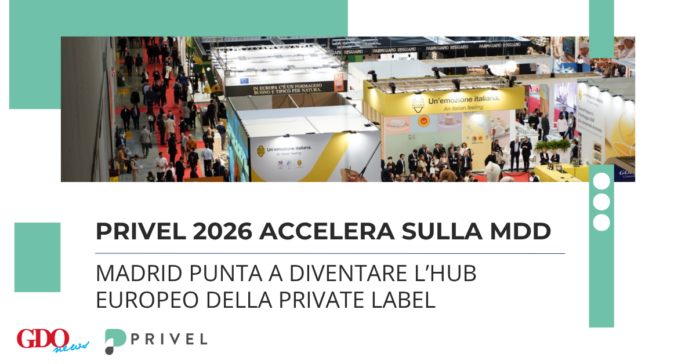 Aerial view of a crowded trade show with multiple booths and attendees, banners reading Italian branding visible in the background.