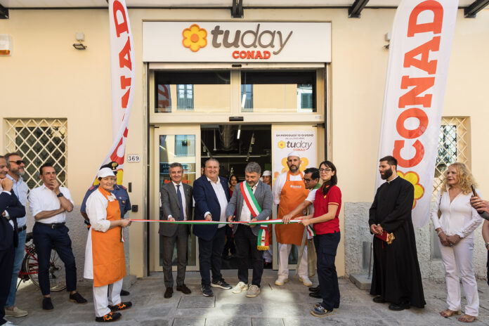 162A0054 copia Group of people at a ribbon-cutting ceremony outside a Conad Today store, with a processed tricolor ribbon and orange aprons among the attendees.