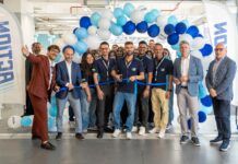 Primo store siciliano per Action: apertura in provincia di Catania Group of employees at a ribbon-cutting ceremony with blue and white balloons in a bright showroom.