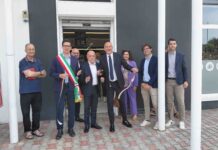 Group of adults in business attire standing outside a storefront for a ribbon-cutting ceremony.