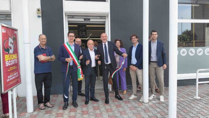 Group of adults in business attire standing outside a storefront for a ribbon-cutting ceremony.