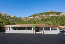 Front of a small storefront with a sign reading 'emporium' against a hillside and clear blue sky.