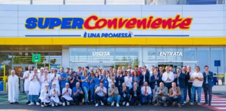 Group of supermarket staff posing in front of a SuperConveniente store entrance.