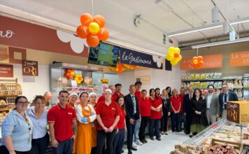 Conad Nord Ovest rinnova lo storico City di Pontremoli Group of supermarket staff and managers posing for a photo under orange and yellow balloons near deli counters and signage.