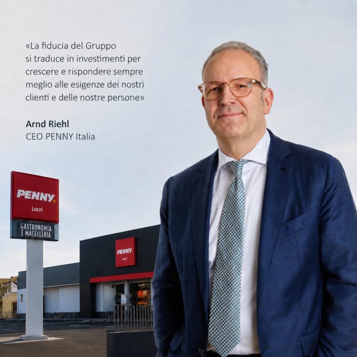 PENNY CEO CEO Arnd Riehl of PENNY Italia stands in a navy suit beside a PENNY store; Italian quote about trust is shown to the left.