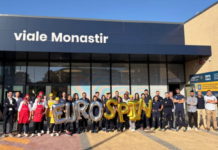 Group of people posing outside a Eurospin store on viale Monastir, holding gold EUROSPIN balloons.
