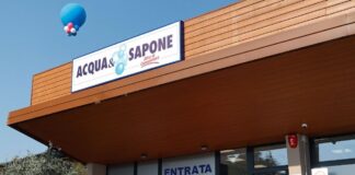 Storefront of Acqua e Sapone with a blue and white sign, balloon decorations, and an entrance labeled Entrata for a festive opening.