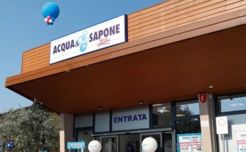 Storefront of Acqua e Sapone with a blue and white sign, balloon decorations, and an entrance labeled Entrata for a festive opening.