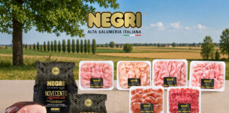 Assorted NEGRI Italian deli meats in plastic trays and black packaging on a wooden table, countryside backdrop with green fields and blue sky.