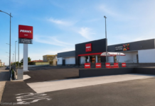 PENNY apre a Locri il primo punto vendita in città Exterior view of a Penny supermarket with a tall sign, red logo, and modern black-and-gray facade under a blue sky.