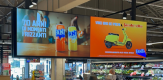 Store interior with a large double-panel advertisement: left shows Fanta cans, right shows a yellow scooter on an orange background.
