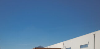 Industrial warehouse with loading docks and ACT-labeled trailers parked outside under a clear blue sky, mountains in the distance.