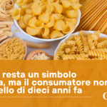 Assorted dry pasta shapes (penne, fusilli, farfalle, spaghetti) spread on a light surface with an orange banner containing Italian text about pasta as a symbol of Italy.