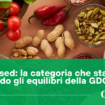Banner showing colorful plant-based foods (tomatoes, peppers, nuts, seeds) with a green overlay text: 'Plant Based: la categoria che sta cambiando gli equilibri della GDO' and GDO data logo.