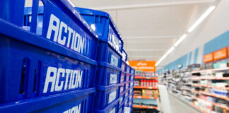 Blue plastic crates labeled 'ACTION' stacked along a supermarket shelf/aisle.