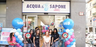 Ribbon-cutting ceremony outside Acqua & Sapone store with pink carpet and blue/pink balloons and staff members smiling.