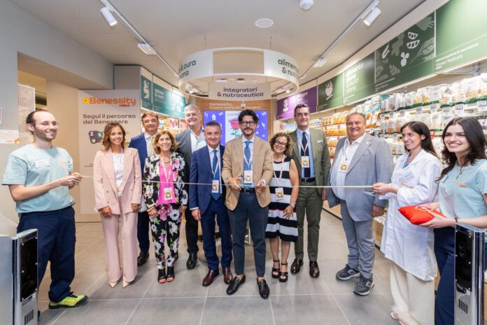 Benessity taglio del nastro Group of professionals in business and casual attire cutting a ribbon in a store aisle during a grand opening ceremony.