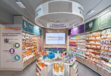 Benessity è la scommessa di Conad oltre il supermercato Wide view of a bright health store aisle with Benessity branding, a central display table, and well-stocked shelves along both sides.