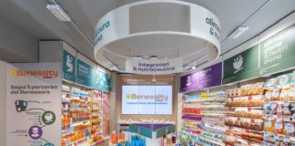 Benessity è la scommessa di Conad oltre il supermercato Wide view of a bright health store aisle with Benessity branding, a central display table, and well-stocked shelves along both sides.
