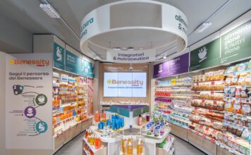 Benessity è la scommessa di Conad oltre il supermercato Wide view of a bright health store aisle with Benessity branding, a central display table, and well-stocked shelves along both sides.