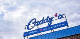 Gruppo DMO cresce in Sardegna con il nuovo Caddy’s di Arzachena Store sign reading "Caddy's" with a blue banner below that says "MAXISTORE ? Oggi mi voglio bene!" against a cloudy sky.