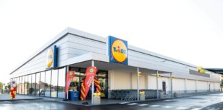 Lidl apre a Terlizzi e porta a 16 gli store tra Bari e provincia Lidl supermarket exterior with the brand logo, entrance framed by red and yellow balloons and promotional banners, shopping carts lined up outside.