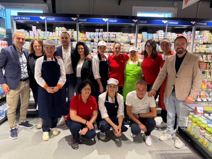 Castel di Lama_Conad Group of supermarket staff posing in the dairy aisle with yogurt and cheese behind them.