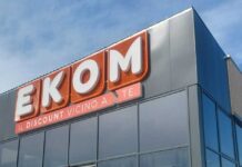 EKOM store sign on a modern building with large orange letters and the slogan 'IL DISCOUNT VICINO A TE' beneath it on a glass-front facade.