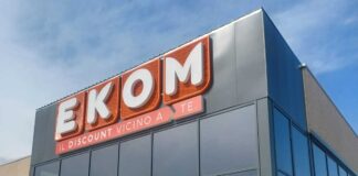 Gruppo Sogegross cresce nello Spezzino con il nuovo Ekom EKOM store sign on a modern building with large orange letters and the slogan 'IL DISCOUNT VICINO A TE' beneath it on a glass-front facade.