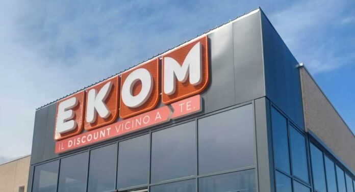 Ekom_Ceparana (1) EKOM store sign on a modern building with large orange letters and the slogan 'IL DISCOUNT VICINO A TE' beneath it on a glass-front facade.
