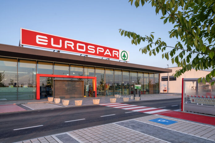 Eurospar EuroSpar supermarket exterior with a large red sign, glass entrance and shopping carts outside on a sunny day.
