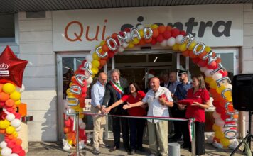 Tuday Conad arriva a Montecchio Emilia nel punto vendita ex Ecu Group of people cutting a ribbon at a store opening under a colorful balloon arch outside the entrance