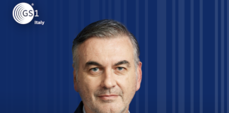 Francesco Avanzini, Presidente GS1 Italy, portrait in a navy suit against a blue striped backdrop with the GS1 Italy logo