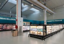 Altasfera debutta in Abruzzo con nuovo il Cash & Carry di San Salvo Interior of a modern supermarket with long refrigerated meat and dairy displays; teal signs read Macelleria and Prodotti Freschi on the walls.