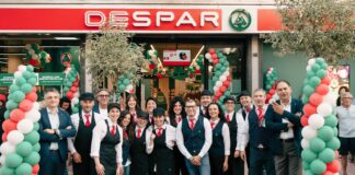 Despar Centro Sud rinnova il punto vendita di Andria con un format di prossimità Group of Spar staff posing outside the store, wearing uniforms, with green, white and red balloon arches for a festive event.