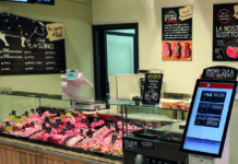 Butcher shop display case with various meat cuts arranged behind a glass counter.