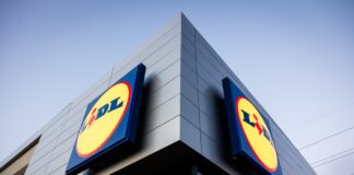 Exterior of a Lidl store with large round yellow and blue logos on a gray, modern building against a blue sky