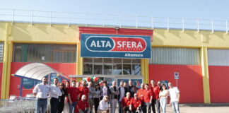 Group photo of employees outside a colorful Alta Sera store in Altamura, with shopping carts nearby and a balloons arch.