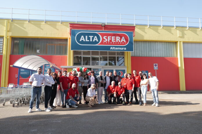 Group photo of employees outside a colorful Alta Sera store in Altamura, with shopping carts nearby and a balloons arch.