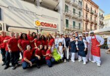 Conad Adriatico riapre lo store di via Di Palma a Taranto con l’area Con Sapore Group of CONAD staff and chefs posing for a photo outside a supermarket on a sunny street.