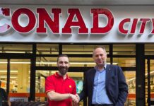 Conad Nord Ovest integra due ex punti vendita Realco nella rete City di Modena Two men shake hands in front of a CONAD City supermarket storefront