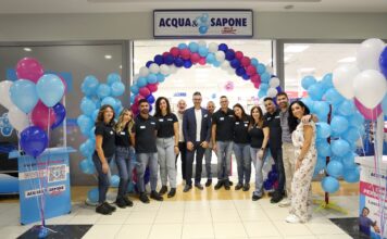 Acqua & Sapone cresce con tre nuove aperture in Liguria, Piemonte e Calabria Staff group posing under a blue-pink balloon arch at Acqua e Sapone store opening ceremony in a shopping center.