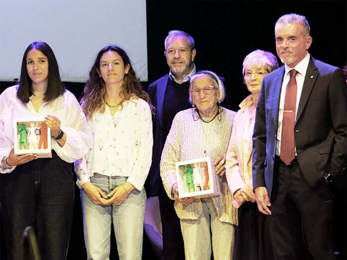Trombone_Lucchi_cooperatrici_dell_anno_2026 Group of six adults on a stage posing for a photo, two women in front hold framed pictures.