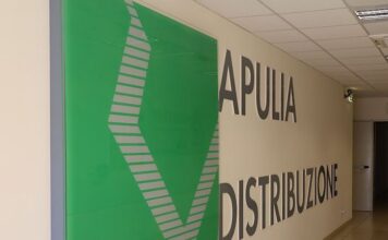 Hallway with large 'APULIA DISTRIBUZIONE' sign on the wall and a green decorative panel on the left.