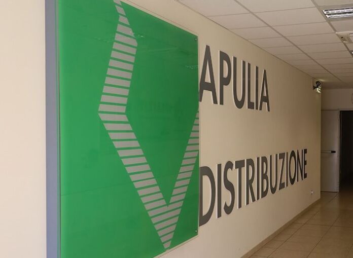Hallway with large 'APULIA DISTRIBUZIONE' sign on the wall and a green decorative panel on the left.