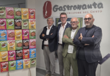 Four men in smart-casual attire pose with crossed arms in front of a wall with the 'Gastronauta' logo and a colorful cereal box display on a stand.