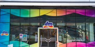 Facade of a dm-drogerie markt with rainbow-tinted glass panels and central entrance door.