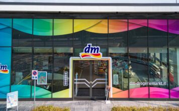 Facade of a dm-drogerie markt with rainbow-tinted glass panels and central entrance door.